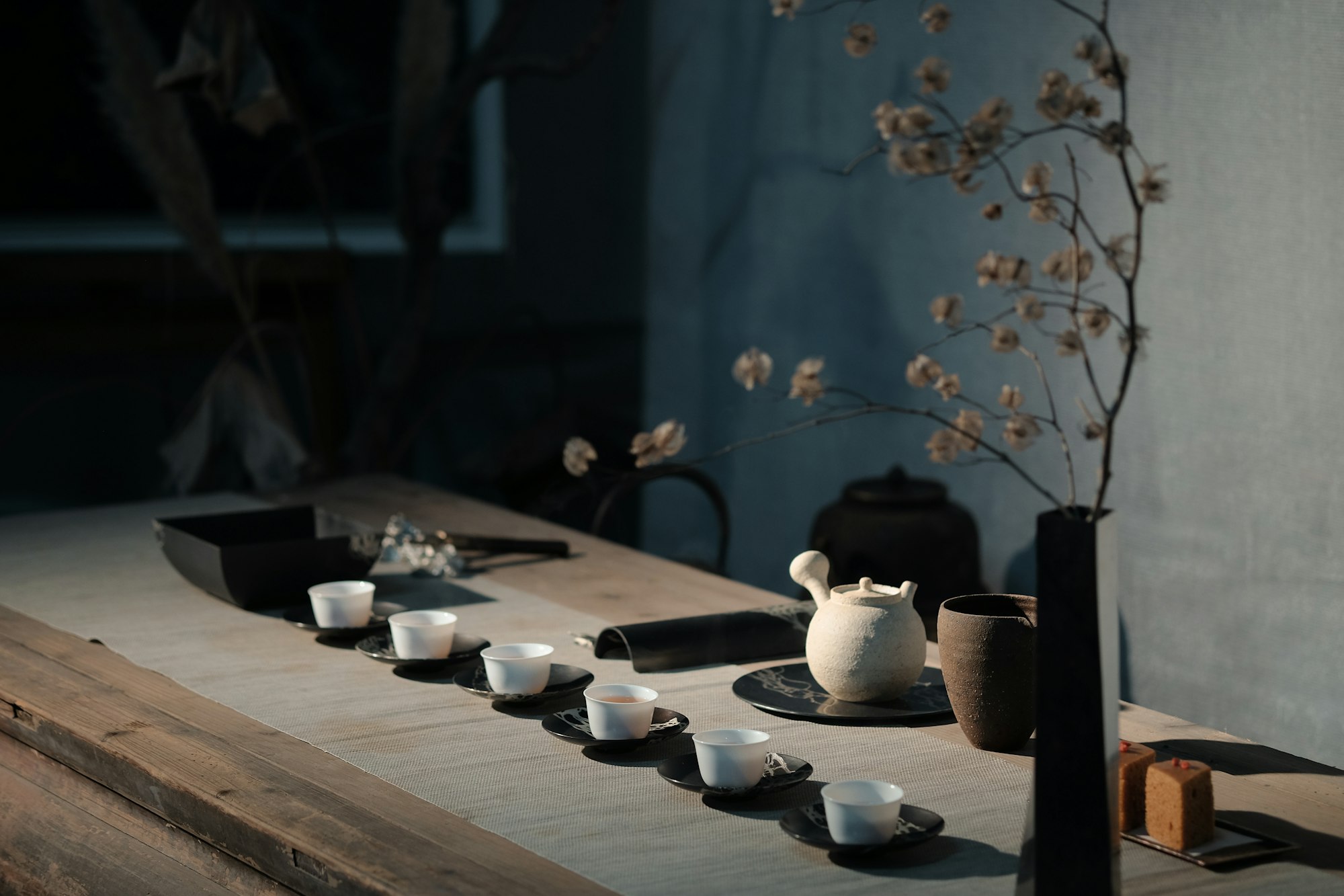 Table de dégustation, petites tasses blanches et théière, lumière douce